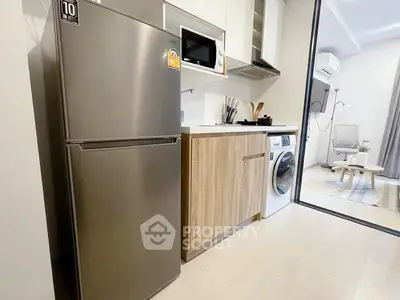 Modern kitchen with stainless steel fridge and washing machine in open layout apartment.