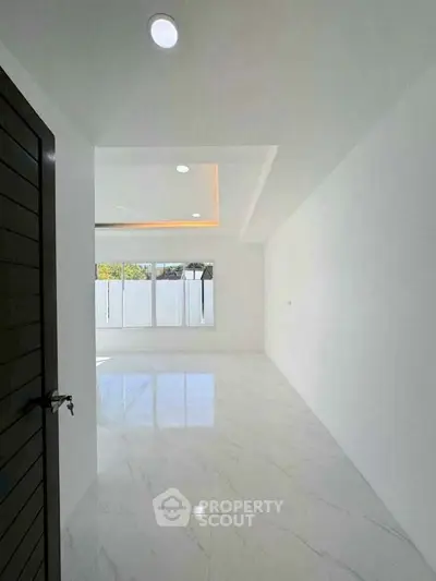 Spacious and bright interior with modern white marble flooring and large windows.