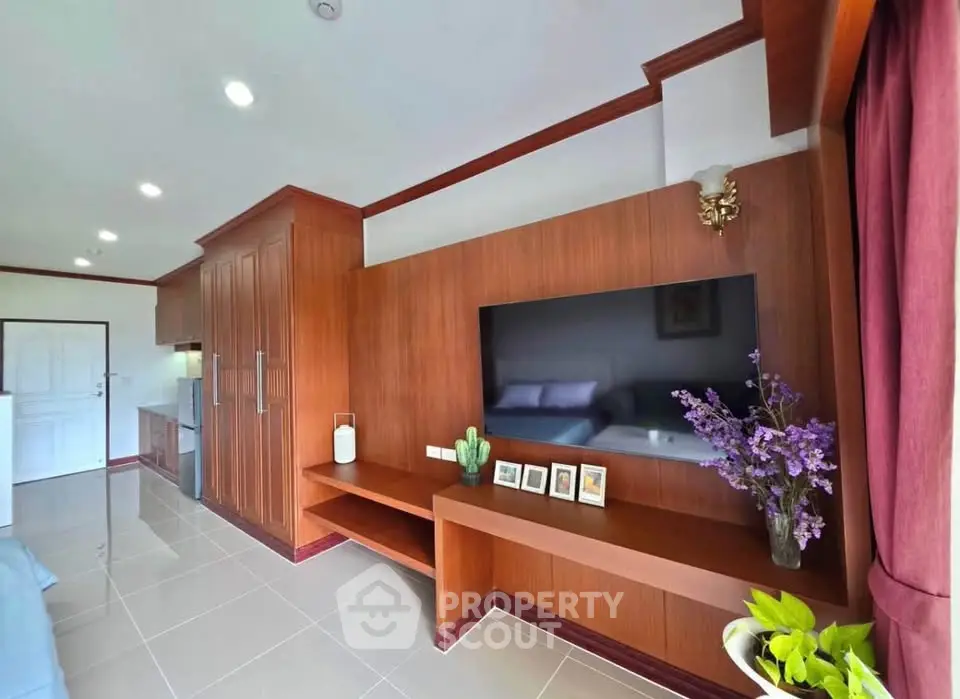 Modern living room with sleek wooden paneling and large TV, perfect for relaxation.
