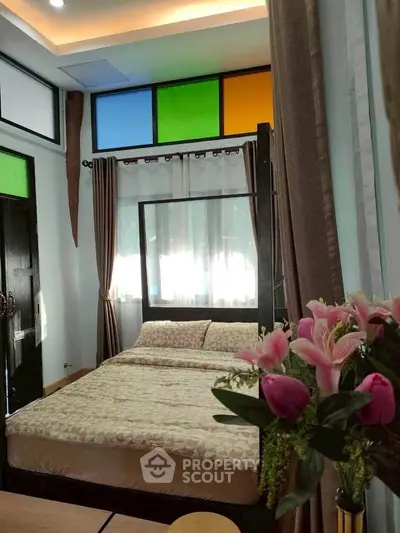 Charming bedroom with colorful windows and cozy bed, perfect for relaxation.