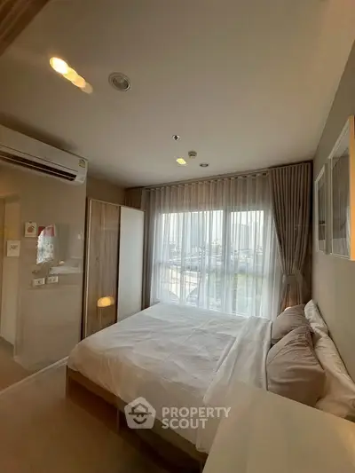 Cozy bedroom with large window and modern furnishings in a stylish apartment.