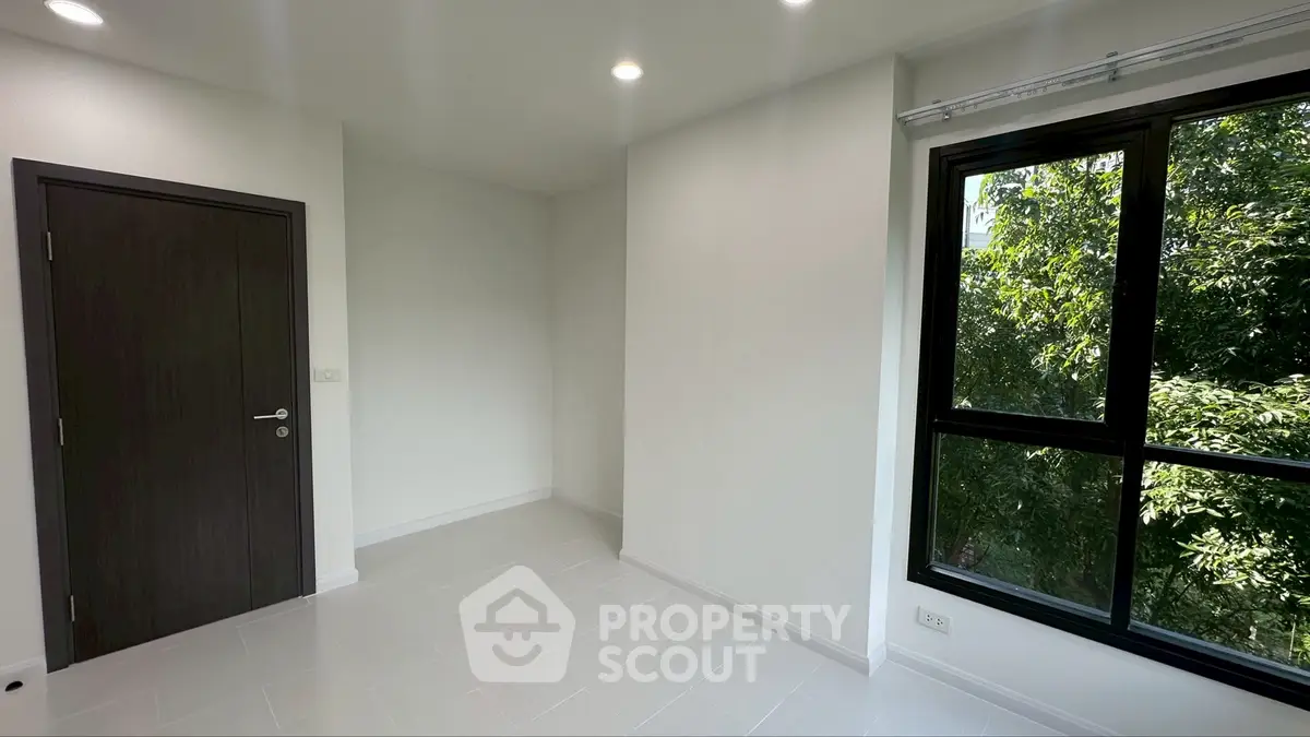 Bright empty room with large window and modern door, perfect for customization.