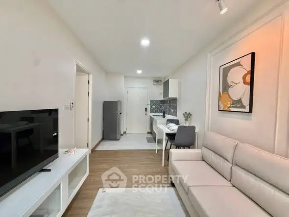 Modern living room with open kitchen, sleek decor, and cozy ambiance.