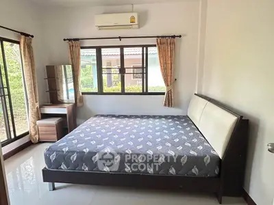 Spacious bedroom with large windows and modern furnishings in a serene setting.