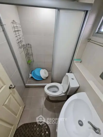 Compact bathroom with shower, toilet, and sink in modern apartment.