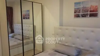 Cozy bedroom with mirrored wardrobe and elegant headboard in modern apartment.