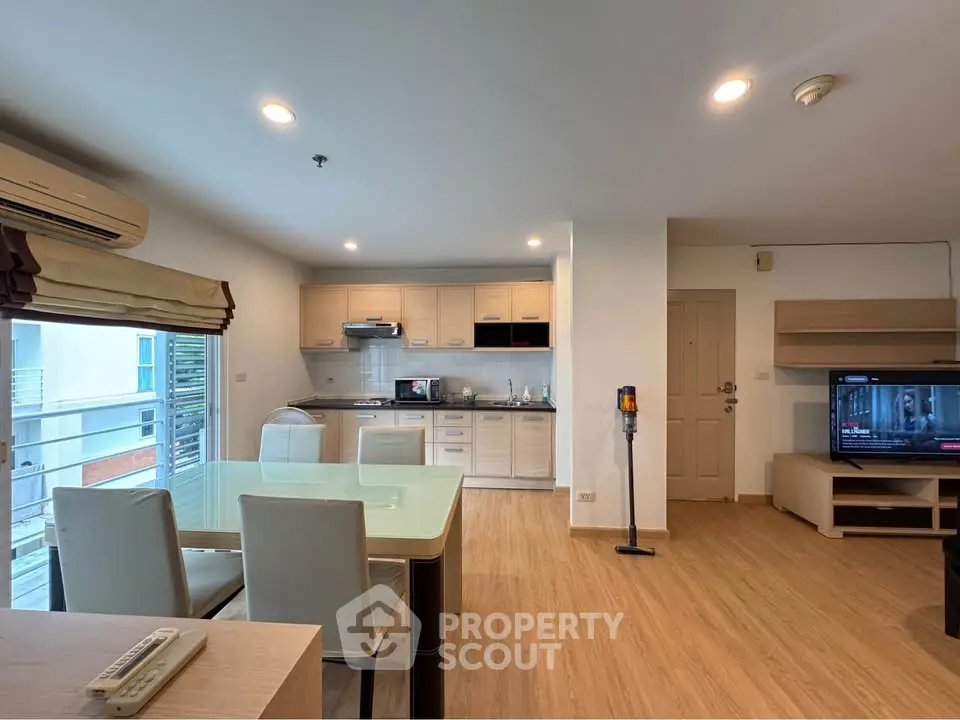 Modern open-layout living room with kitchen, featuring wooden flooring and stylish furniture.