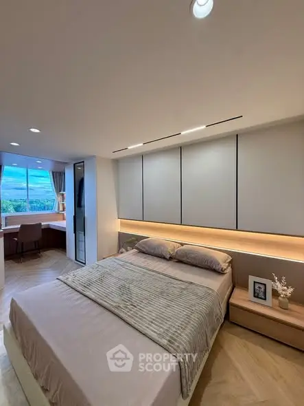 Modern bedroom with cozy lighting and scenic window view, featuring elegant decor and a stylish workspace.