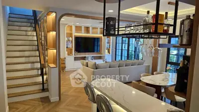 Luxurious open-plan living room with modern kitchen and elegant staircase, perfect for entertaining.