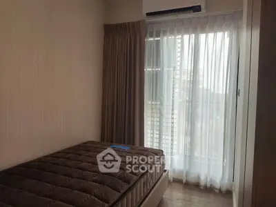 Cozy bedroom with natural light and city view, featuring a comfortable bed and elegant curtains.