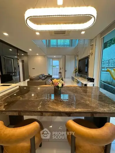 Luxurious open-plan living room with elegant marble dining table and modern lighting