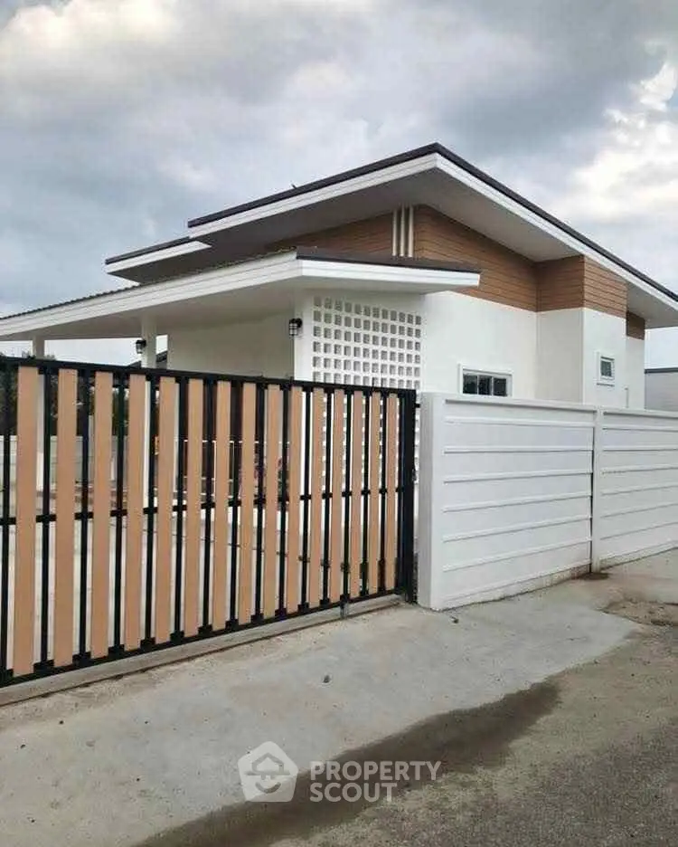 Modern single-story house with stylish wooden accents and secure gated entrance.