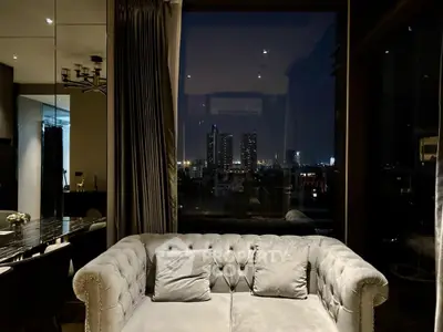 Luxurious living room with plush sofa and stunning city night view through large window.