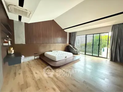 Spacious modern bedroom with large windows and wooden flooring, featuring a minimalist design and garden view.