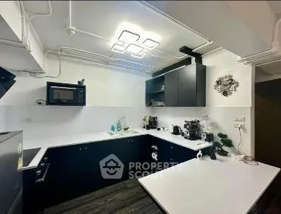 Modern kitchen with sleek black cabinets and white countertops, featuring built-in appliances and stylish lighting.