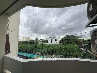 Spacious balcony with lush green view and air conditioning units, perfect for relaxation.