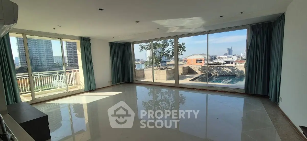 Spacious living room with large windows offering stunning city views and abundant natural light.