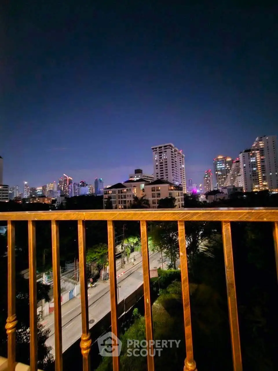 Stunning city skyline view from a balcony at night, showcasing urban living.