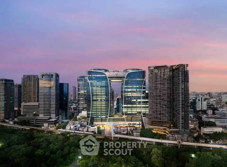 Stunning cityscape view of modern skyscrapers at sunset with lush greenery in the foreground.