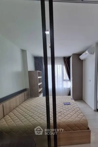 Modern bedroom with glass partition and natural light, featuring a cozy bed and stylish shelving.