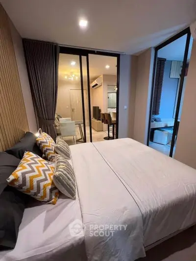 Modern bedroom with stylish decor and view into living area, featuring cozy ambiance and elegant design.
