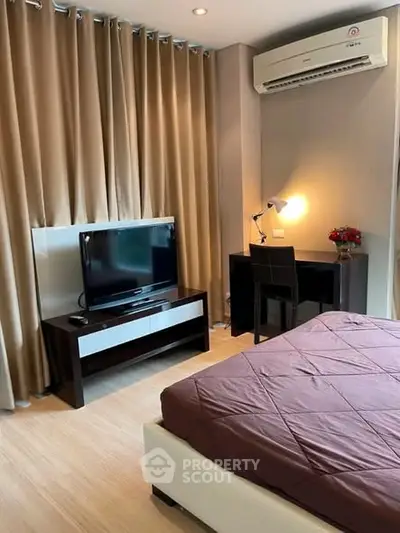 Cozy bedroom with TV, desk, and air conditioning, perfect for relaxation and work.