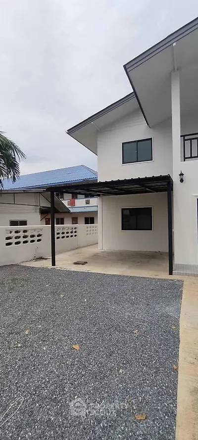 Modern two-story house with carport and gravel driveway