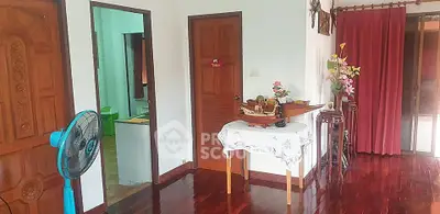 Charming interior with wooden floors and decorative accents, featuring a fan and floral arrangements.