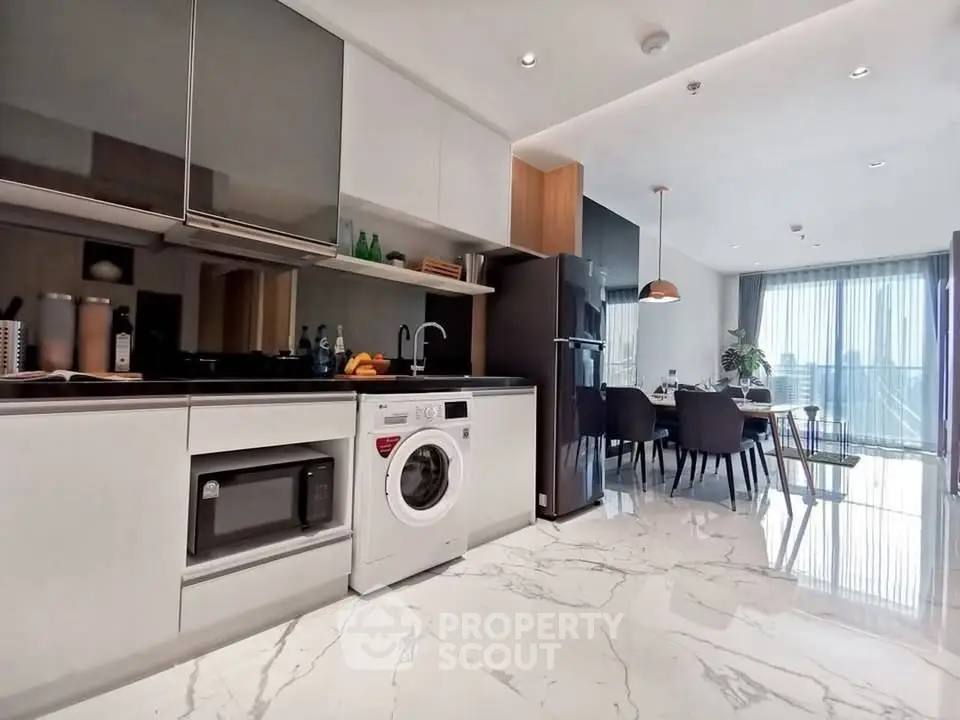 Modern kitchen with sleek appliances and dining area in open layout apartment.