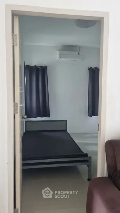 Cozy bedroom with minimalist design featuring a metal bed frame and air conditioning.