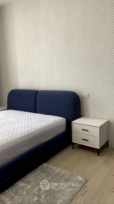 Modern bedroom with stylish blue bed and chevron wallpaper