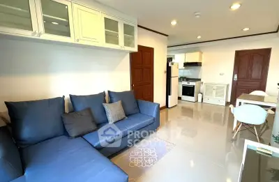 Modern living room with blue sofa and open kitchen layout in stylish apartment.