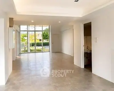 Spacious open-plan living area with large windows and garden view, perfect for modern living.
