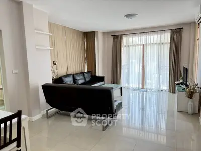 Spacious modern living room with sleek black sofa and large windows for natural light.