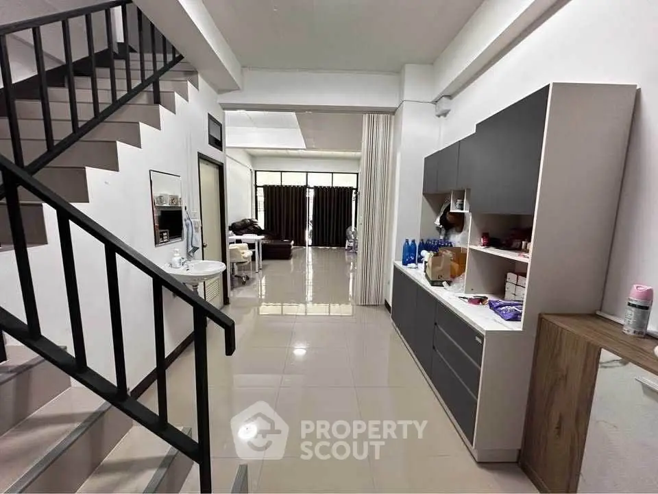 Modern open-plan living area with sleek staircase and stylish kitchen cabinetry.