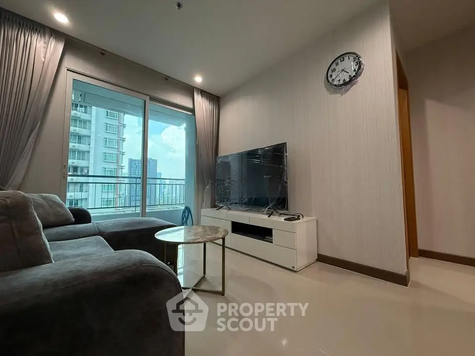 Modern living room with large TV and balcony view in high-rise apartment