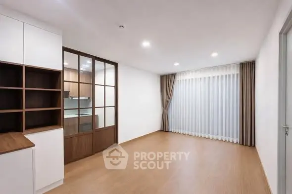 Spacious modern living room with wooden flooring and large window, perfect for cozy gatherings.