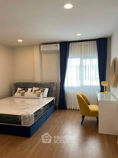 Modern bedroom with stylish decor, featuring a cozy bed, elegant curtains, and a chic yellow chair.