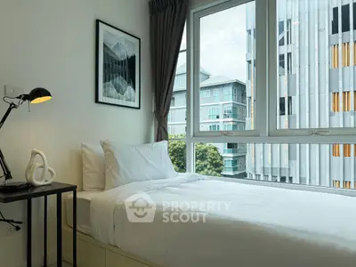 Modern bedroom with large window and city view, featuring stylish decor and natural light.