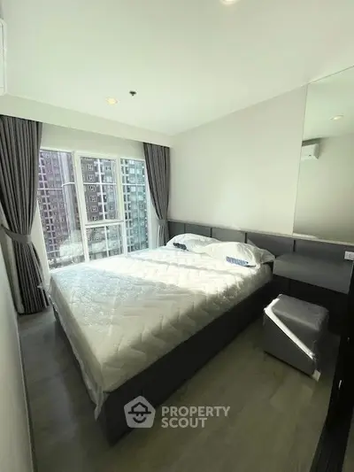 Modern bedroom with large window and city view, featuring sleek furniture and elegant decor.