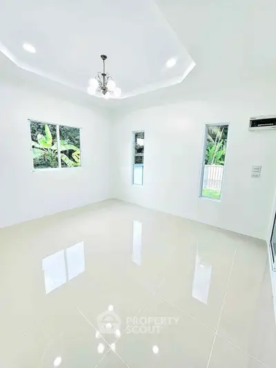 Bright and spacious living room with glossy tiled floors and elegant chandelier.