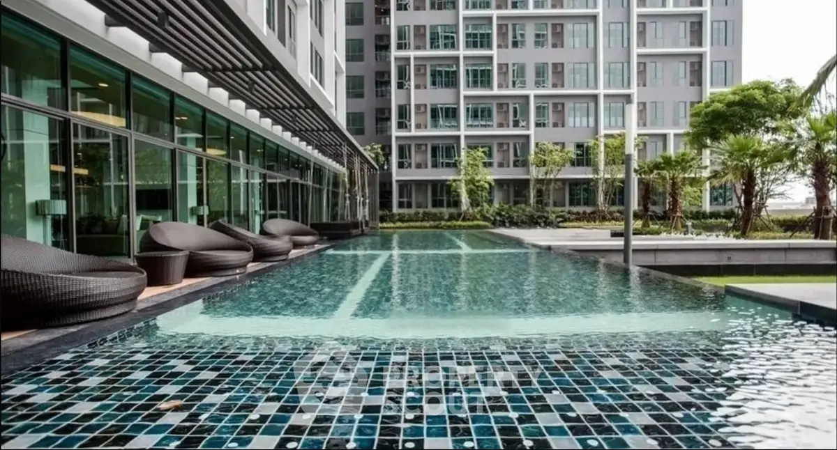 Luxurious apartment complex with modern pool and stylish outdoor seating area.