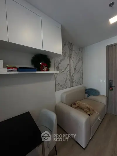 Modern living room with stylish sofa and marble accent wall in a cozy apartment.