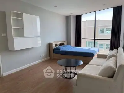 Modern studio apartment with large window and stylish furnishings