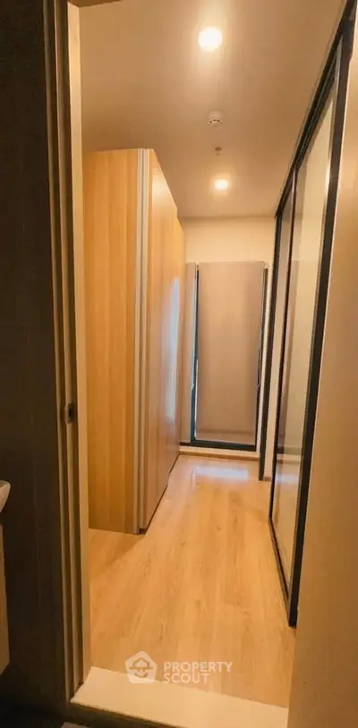 Modern hallway with wooden flooring and sliding glass doors in a stylish apartment.