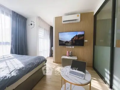 Modern bedroom with stylish decor, wall-mounted TV, and natural light.