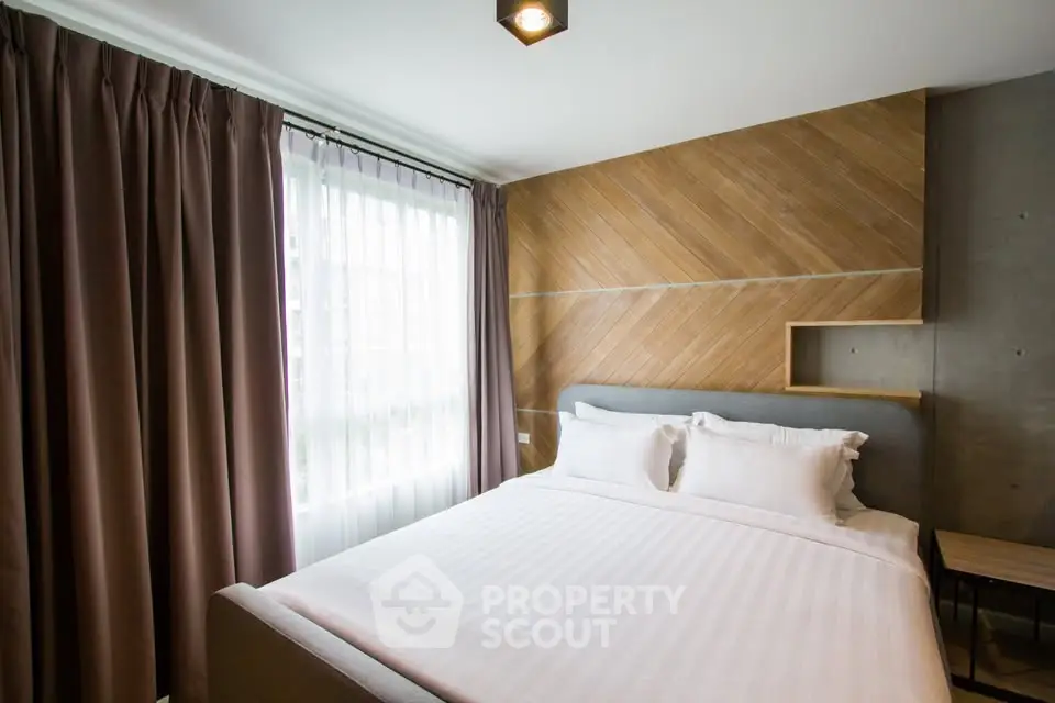 Modern bedroom with stylish wood paneling and large window for natural light.