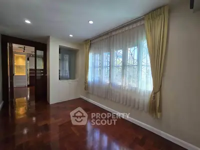 Spacious room with elegant wooden flooring and large window with curtains, perfect for a cozy living space.