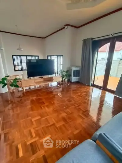 Spacious living room with polished wooden floors and large windows for natural light.