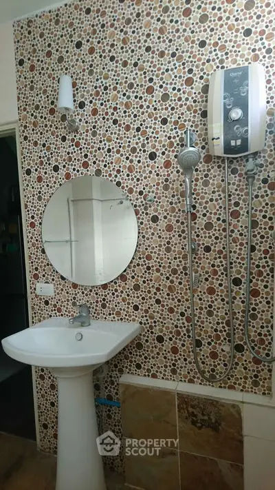 Stylish bathroom with unique mosaic wall and modern shower fixtures.